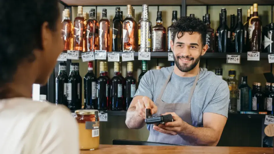 Liquor store worker checking a customer out 